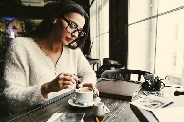 Femme réfléchie remue le sucre dans une tasse de café