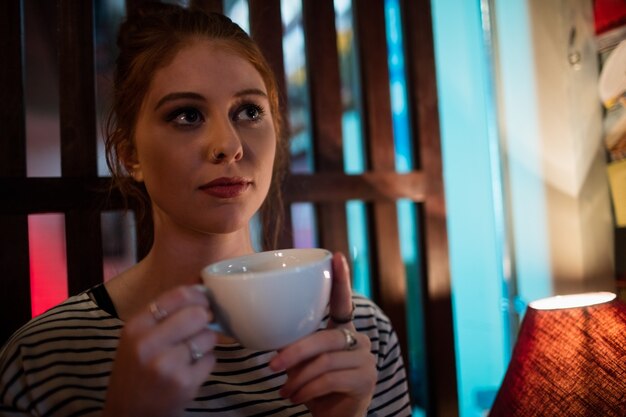 Femme réfléchie tenant une tasse de café