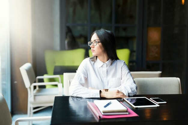 Femme réfléchie travaillant au café