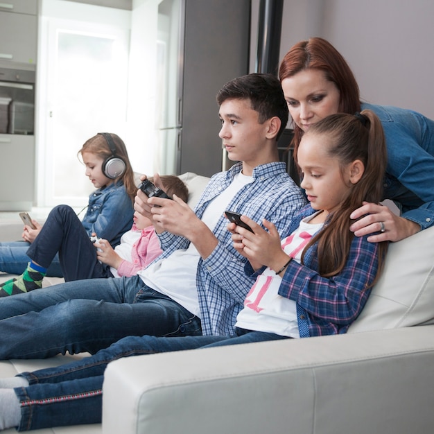 Femme regardant adolescent et fille jouant à des jeux vidéo