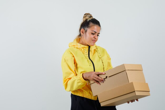 Femme regardant des boîtes en carton en costume de sport et à la recherche concentrée. vue de face.