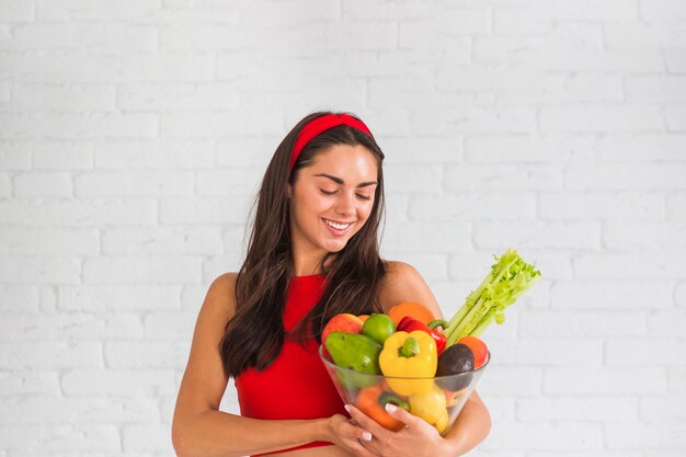 Femme regardant les légumes frais et les fruits dans le bol en verre