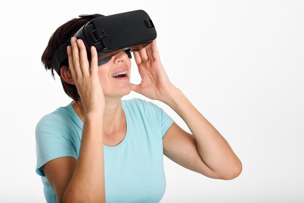 Femme regardant des lunettes VR et gesticulant avec ses mains.