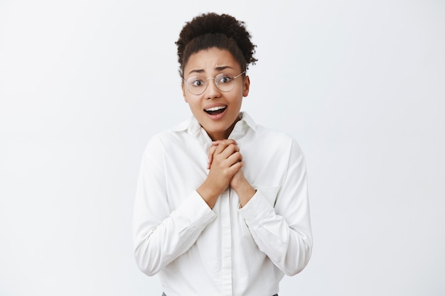 Femme regardant un mélodrame réconfortant à la télévision, sympathisant personnage principal, regardant toucher et charmante peau, haletant, tenant les mains ensemble sur la poitrine, regardant le mur gris