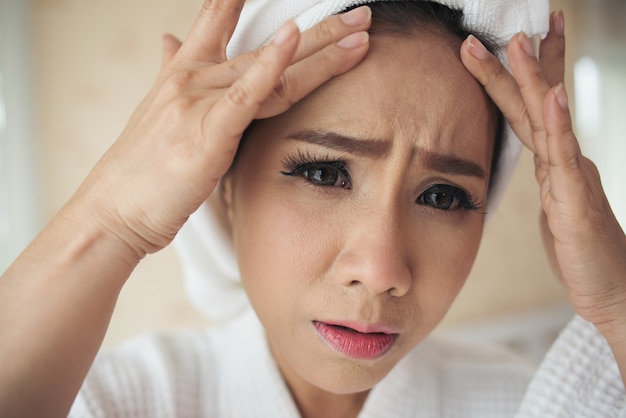 femme regardant miroir à la maison et vérifiant son visage