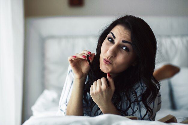 Femme regardant avec plaisir la caméra sur le lit