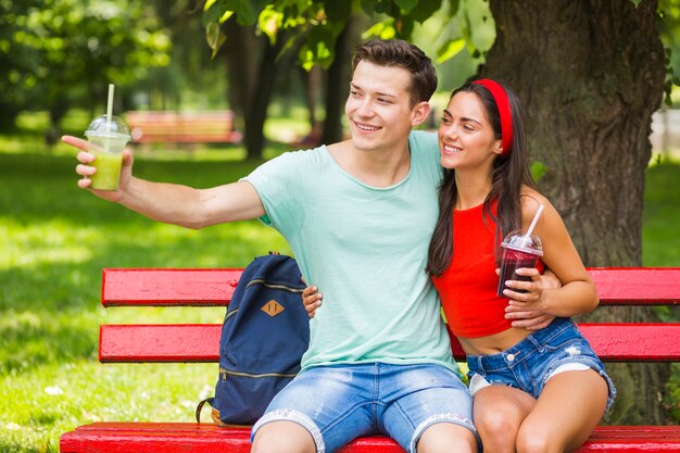 Femme regardant son petit ami pointant vers quelque chose tenant des smoothies sains