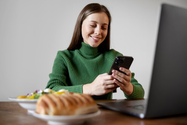 Femme regardant son smartphone en mangeant son repas