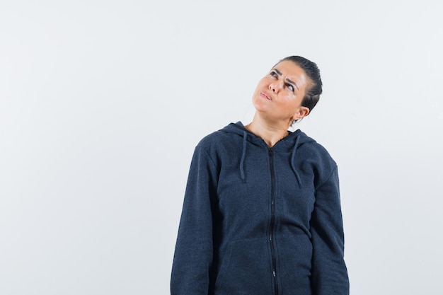 Femme regardant en sweat à capuche et à la vue de face, hésitante.