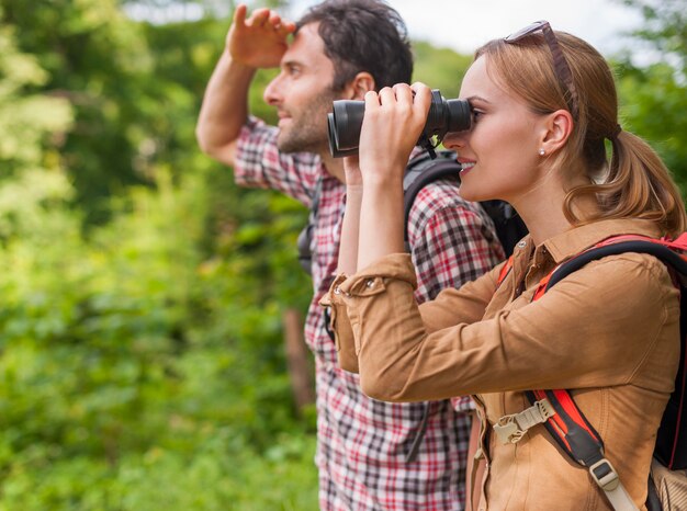 Femme regardant à travers les jumelles. Temps de marche