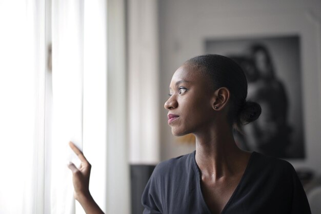 Femme regarde par la fenêtre