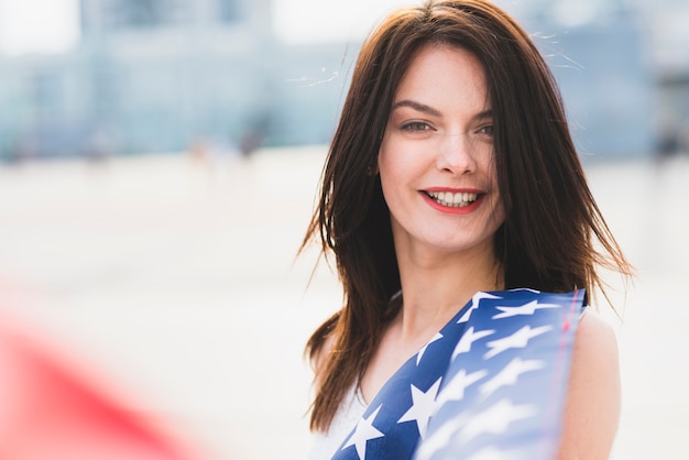 Femme, regarder caméra, et, sourire, agitant, à, étoiles drapeau américain