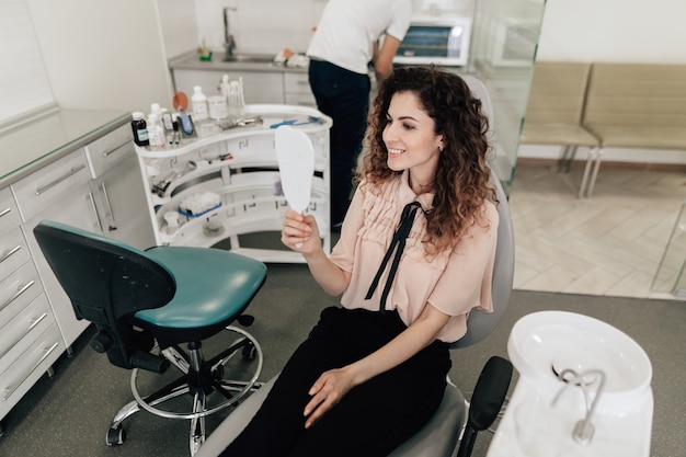 Femme, regarder dents, miroir, rendez-vous chez le dentiste