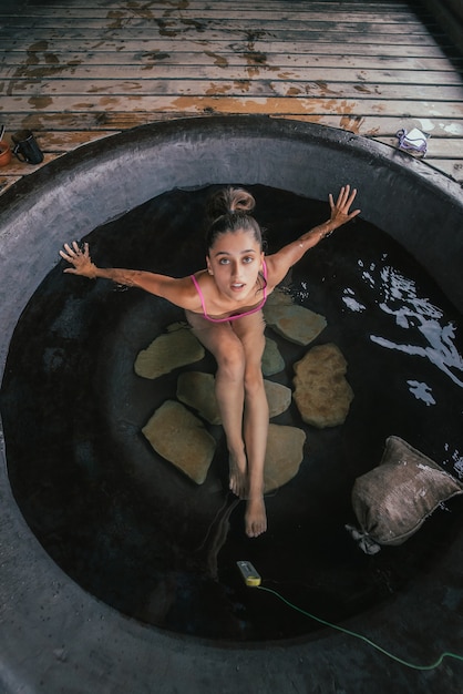 Photo gratuite femme relaxante dans un bain extérieur rond soins de la peau bio dans un bain chaud