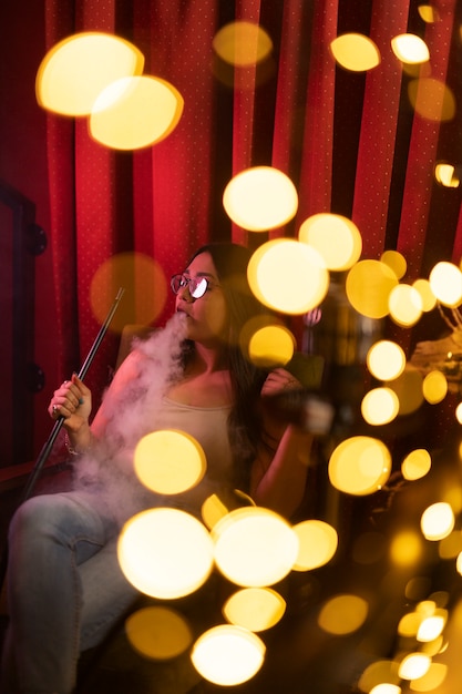 Femme relaxante en vapotant d'un narguilé dans un bar