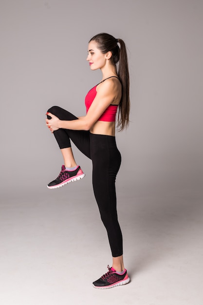 Femme de remise en forme faisant des exercices d'étirement. Jeune femme sur un mur blanc. Étirement et motivation