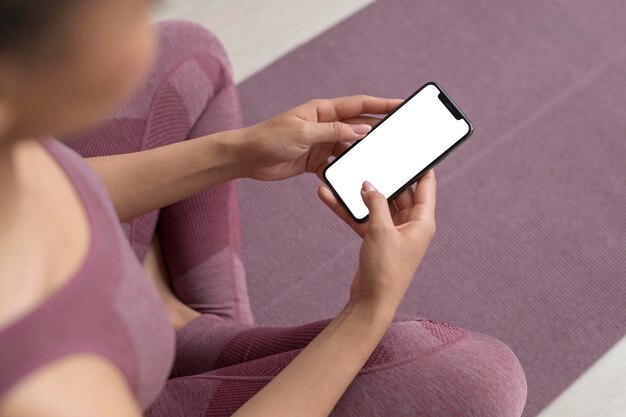 Femme de remise en forme tenant un smartphone avec écran blanc