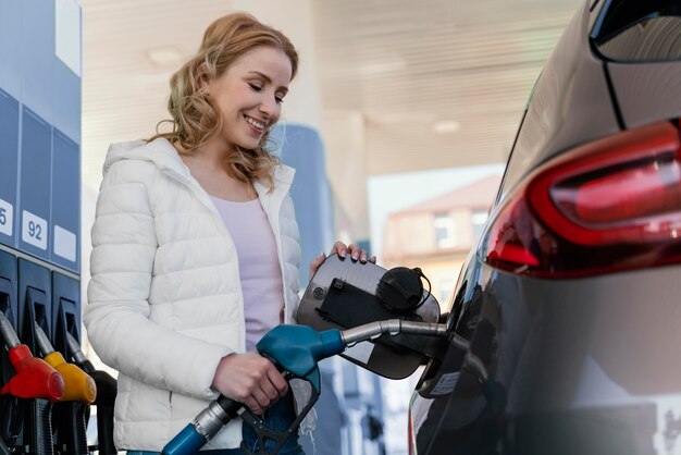 Une femme remplit la voiture à la station-service.