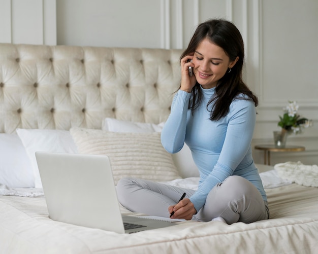 Femme restant dans son lit tout en travaillant