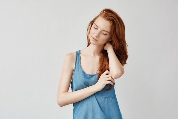 Femme rêveuse avec des taches de rousseur pensant toucher les cheveux.