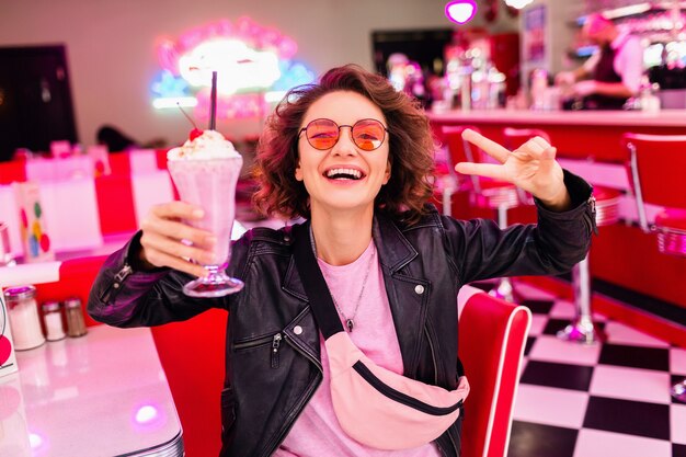 Femme riante élégante dans un café rétro vintage des années 50 assis à table