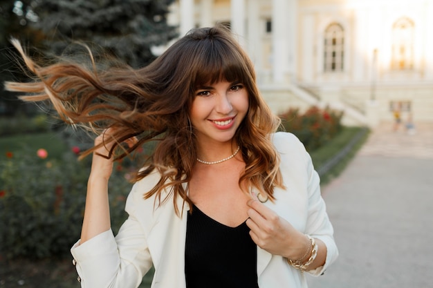 Femme riante heureuse jouant avec des cheveux et profiter de la journée d'automne dans la ville européenne. Look élégant.