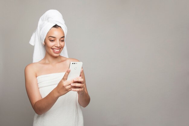 Femme rire et envoyer des messages après le bain