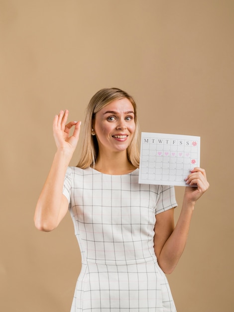 Femme en robe blanche montrant son calendrier