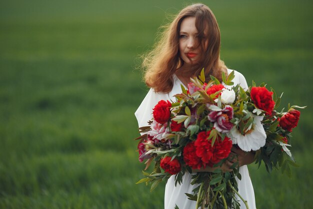 Femme en robe élégante debout dans un champ d'été