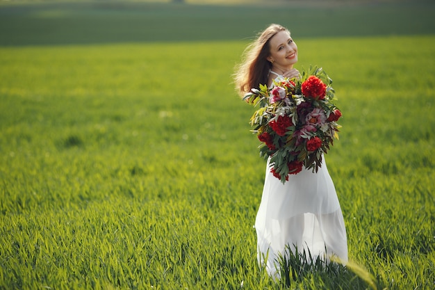 Femme en robe élégante debout dans un champ d'été