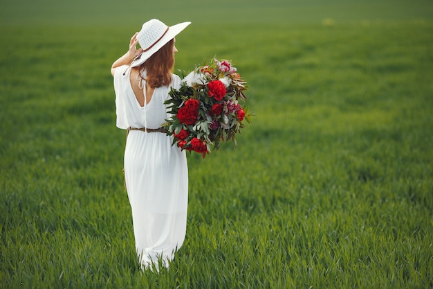 Femme en robe élégante debout dans un champ d'été