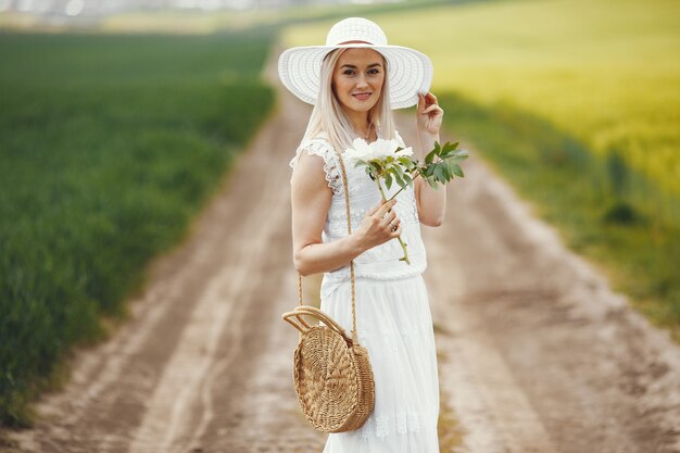 Femme en robe élégante debout dans un champ d'été