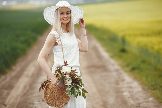 Femme en robe élégante debout dans un champ d'été