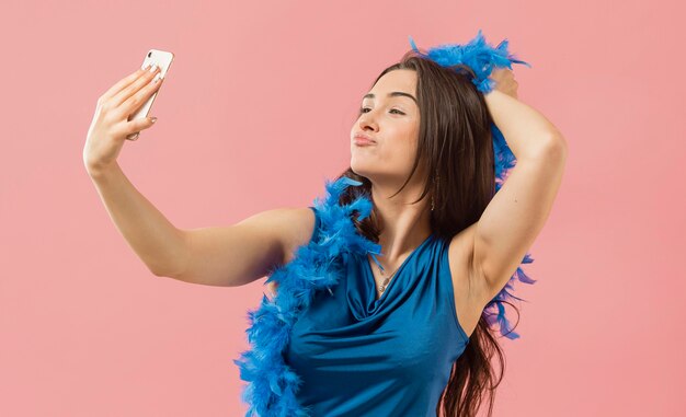 Femme en robe élégante portant des lunettes de soleil à la fête en prenant selfie