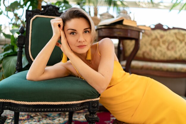 femme en robe d'été jaune avec une coiffure courte dans une chambre d'intérieur de style vintage boho posant