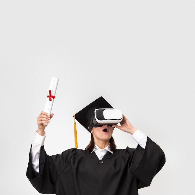 Femme avec robe de graduation et casquette portant un casque de réalité virtuelle
