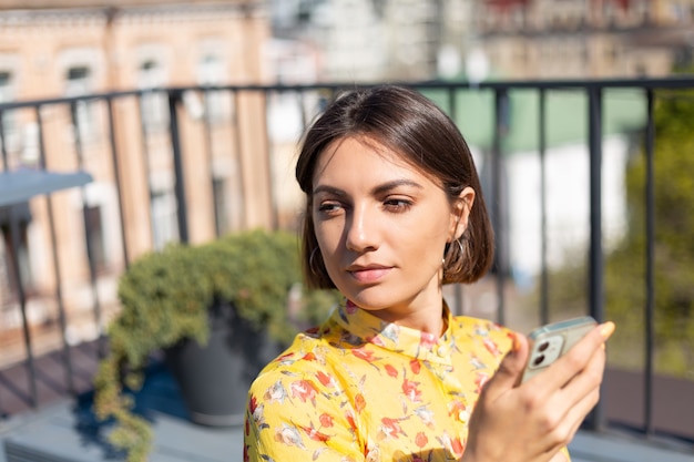 Femme En Robe Jaune Sur La Terrasse Au Café D'été Avec Téléphone Mobile à La Journée Ensoleillée