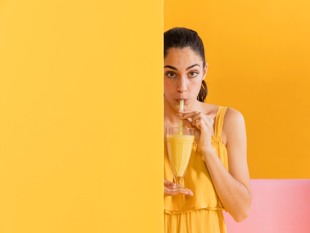 Photo gratuite femme en robe jaune avec un verre de jus