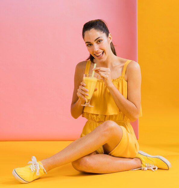 Femme en robe jaune avec un verre de jus