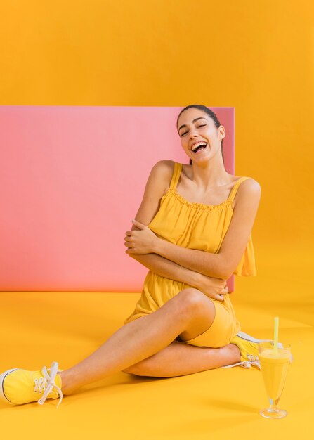 Femme en robe jaune avec un verre de jus