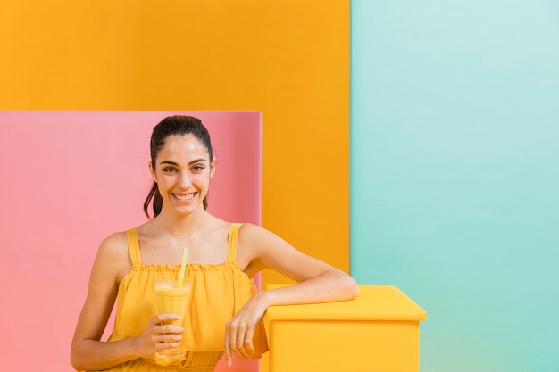 Femme en robe jaune avec un verre de jus