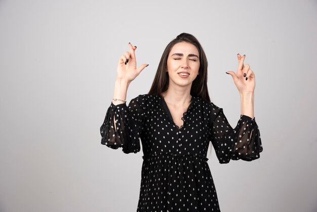 Femme en robe noire faisant des signes avec ses mains.