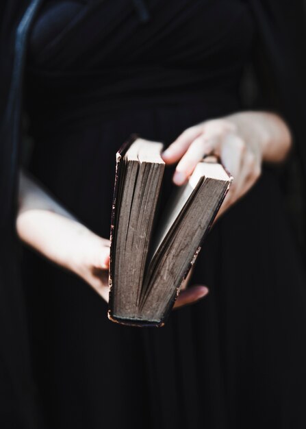 Femme en robe noire tenant un livre ancien