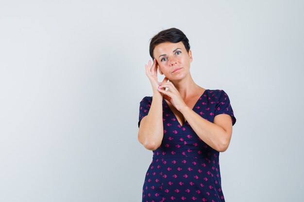 Femme en robe touchant la peau de son visage et à la belle