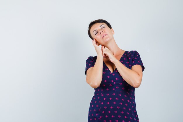 Femme en robe touchant la peau de son visage et à la paix