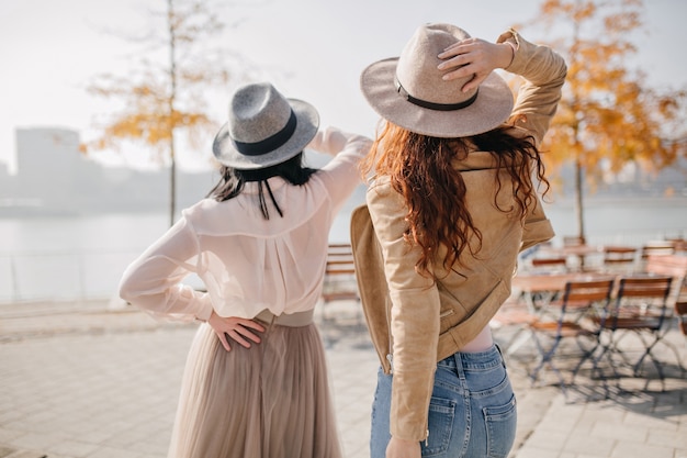 Femme romantique au chapeau gris décoré de ruban porte une jupe élégante en chaude journée d'automne