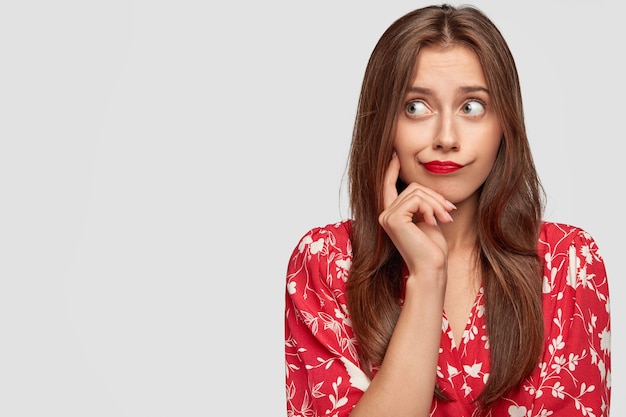 femme avec rouge à lèvres posant contre le mur blanc