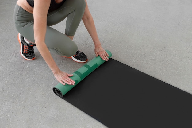 Femme roulant un tapis de yoga