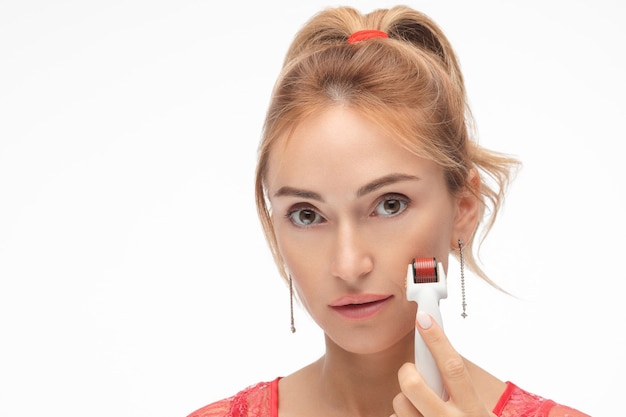 Femme avec rouleau de mésothérapie à micro-aiguille. Isoler sur blanc.