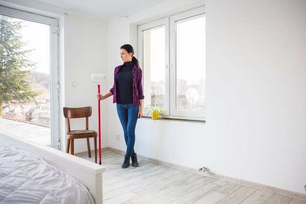 Femme avec rouleau à peinture dans un nouvel appartement
